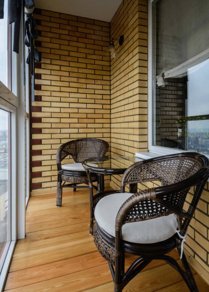 Chaises en osier sur le balcon d'une maison en brique
