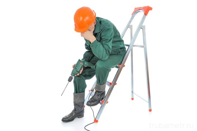 o construtor se senta com uma furadeira em uma escada